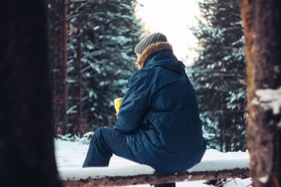 Side view of man sitting on snow covered land