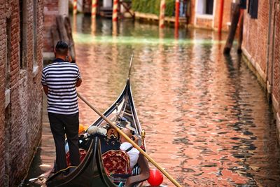 Rear view of people traveling in gondola on canal