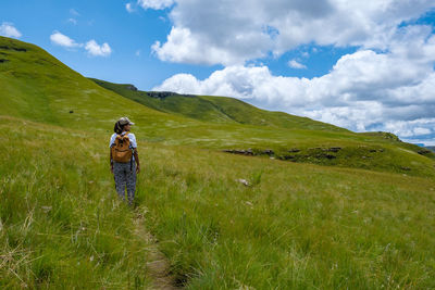 Rear view of woman walking on trail against sky