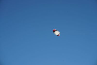Low angle view of person paragliding against clear blue sky