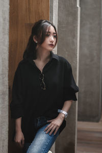 Portrait of young woman standing against wall