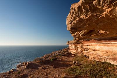 Rock formations by sea against clear sky