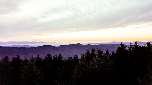 Scenic view of mountains against cloudy sky during sunset