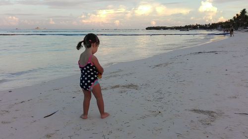 Full length of girl standing on beach against sky during sunset