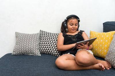 Young woman using phone while sitting on sofa