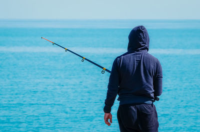 Rear view of man fishing in sea