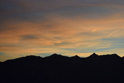 Silhouette mountain against cloudy sky during sunset