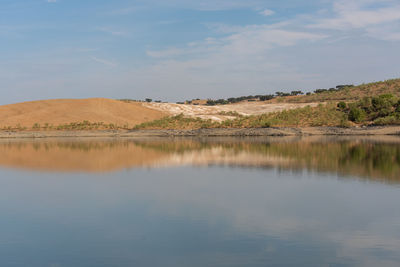 Desert like hill landscape with reflection on the water on a dam lake reservoir in terena, portugal