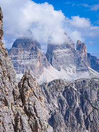 Full frame view of rocky mountains against partially cloudy sky