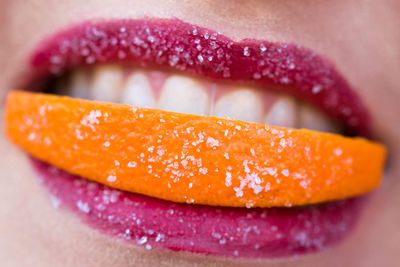 Close-up of woman biting orange slice