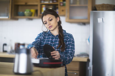 Young woman cleaning an untensil in the kitchen