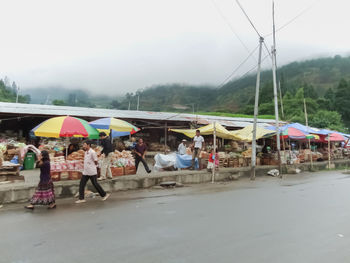 People on road against sky during rainy season