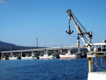 Sailboats moored in sea against clear blue sky