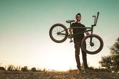 Full length portrait of man with bicycle against sky