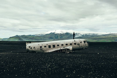 Abandoned airplane on snowy landscape against sky