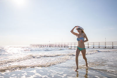 Full length of young woman wearing hat walking on beach