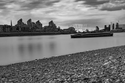 View of buildings by river against cloudy sky