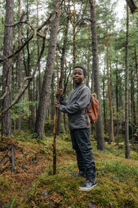 Portrait of boy standing in forest holding stick during vacation