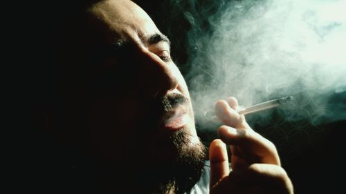 Close-up of man smoking in dark