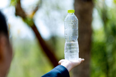 Midsection of man holding bottle against blurred background