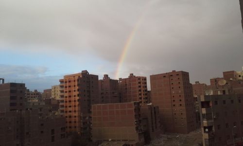 Rainbow over city against sky