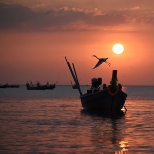 Silhouette ship in sea against sky during sunset