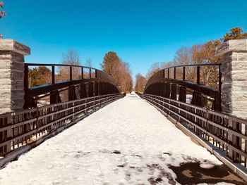 Snow covered footbridge against sky