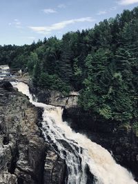 Scenic view of waterfall in forest against sky