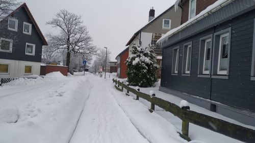 Snow covered houses by buildings in city