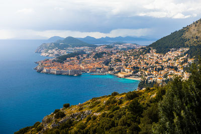 Aerial view of townscape by sea against sky