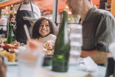 Smiling girl having food with father while sitting at restaurant