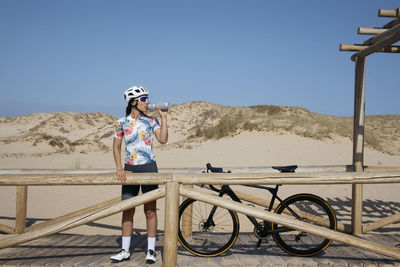 Cyclist drinking water with bottle on sunny day