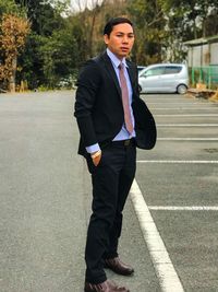 Portrait of businessman standing on road in city