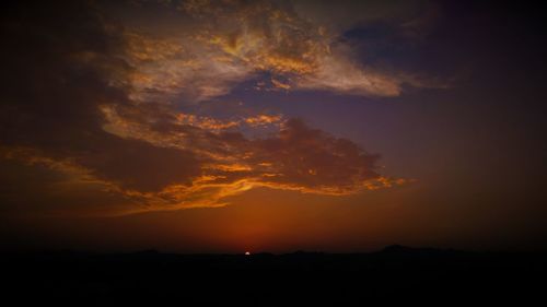 Silhouette landscape against dramatic sky during sunset