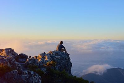 Young woman perching on mountain against sky