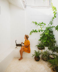 Young woman sitting by potted plant at home