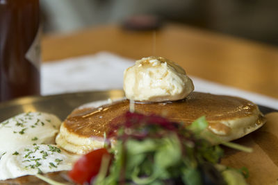 Close-up of pancakes with salad and poached egg in plate on table