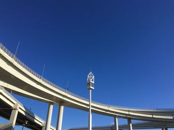 Low angle view of suspension bridge against clear blue sky