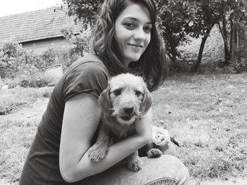 Portrait of woman holding dog on field