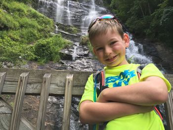 Portrait of boy standing against waterfall