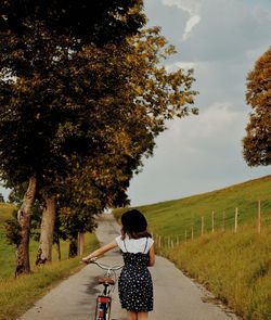 Rear view of man riding bicycle on footpath