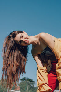 Portrait of young woman standing against blue sky