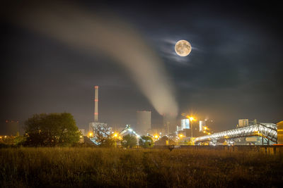 Illuminated factory against sky at night