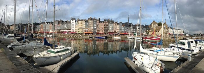 Boats in harbor against cloudy sky