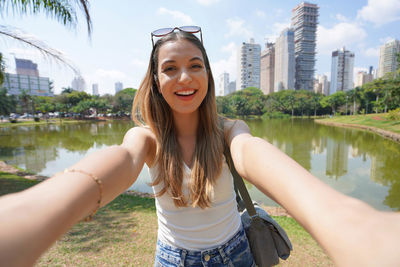 Portrait of smiling brazilian girl takes selfie in vaca brava park in goiania, goias, brazil