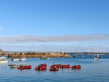 Boats in sea against clear blue sky