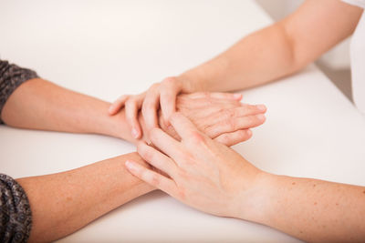 Midsection of woman holding hands over white background