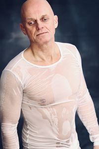 Portrait of man standing against black background