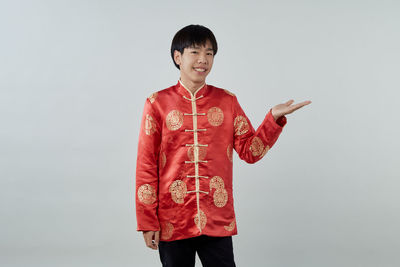 Portrait of smiling boy standing against gray background