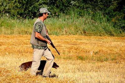 Side view of hunter walking with dog on land